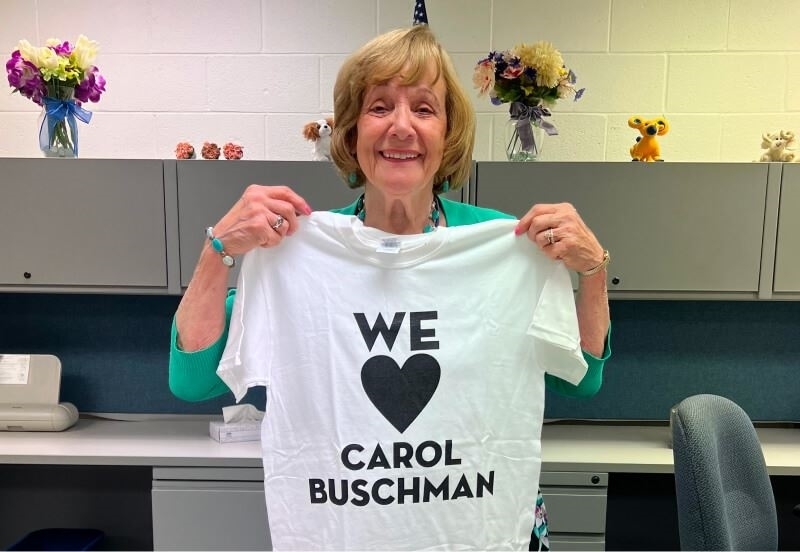 Carol holding 'We Love Carol Buschman' t-shirt